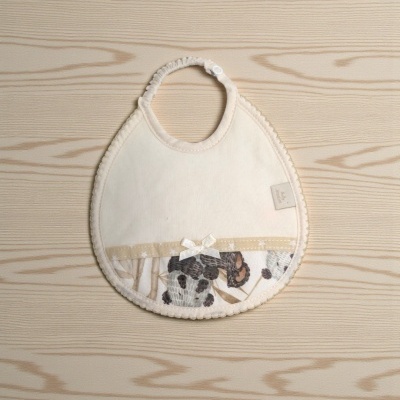 Babete de bebé bege com padrão floral cinza e castanho e laço branco
