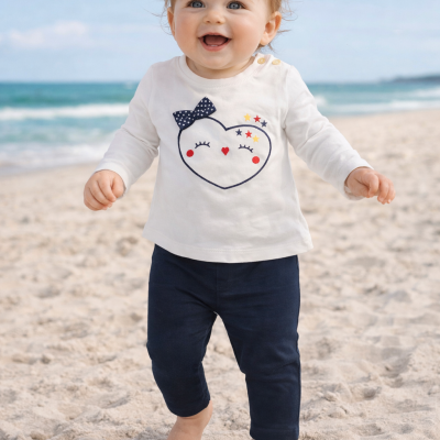 Bebé com roupa branca e azul na praia