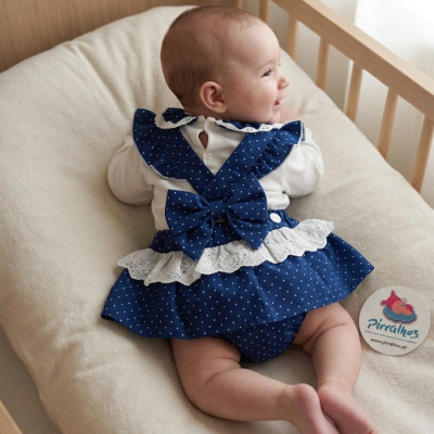 Bebé deitado de bruços com vestido azul de bolinhas brancas e laço