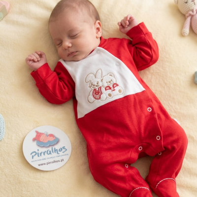 Bebé deitado com macacão vermelho e branco bordado, ao lado logótipo Pirralhos.