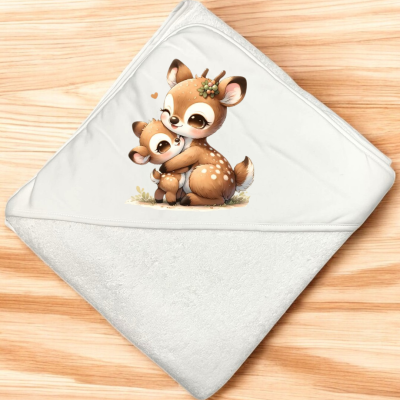 Toalha branca com capuz e desenho de dois veados castanhos abraçados sobre fundo de madeira