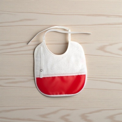 Babete de bebé branco e vermelho sobre mesa de madeira clara
