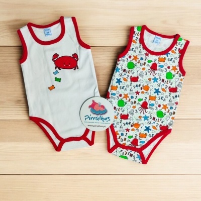 Dois bodies de criança com tema marinho sobre superfície de madeira clara