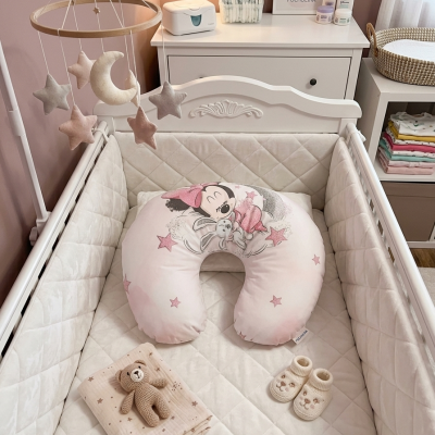 Berço branco com almofada Minnie cor-de-rosa e móbile de estrelas e lua em quarto de bebé