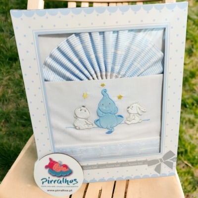 Conjunto de roupa de cama para bebé azul e branco com desenho bordado de elefante e coelhos numa embalagem decorativa.