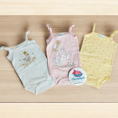 Três bodies de bebé com estampados de cisnes e estrelas sobre fundo claro.