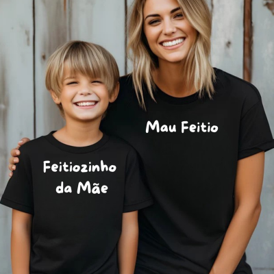 Criança e mulher sorridentes com t-shirts pretas com frases em branco, de pé junto a uma parede metálica cinzenta