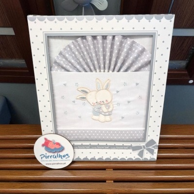 Fralda de bebé bordada com coelho em embalagem branca decorada com padrão de pontos cinzentos
