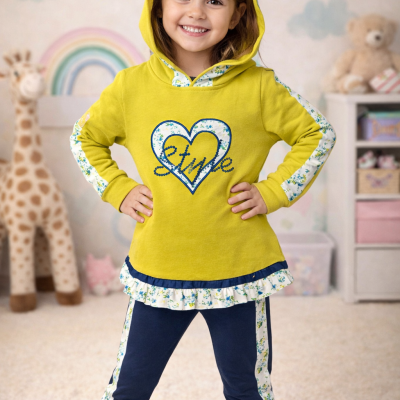 Menina com capuz amarelo e detalhes florais posando em quarto infantil