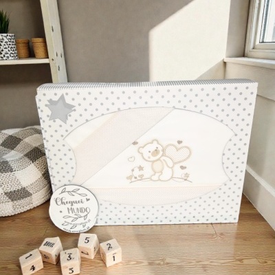 Caixa branca com pontos cinzentos e roupinha de bebé com ursinho estampado