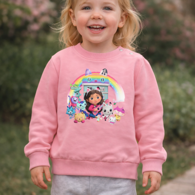 Criança com sweatshirt cor-de-rosa estampada a personagens animados e calças cinza ao ar livre.