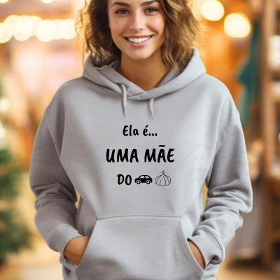 Mulher com sweatshirt cinza com texto e símbolos em preto num ambiente iluminado