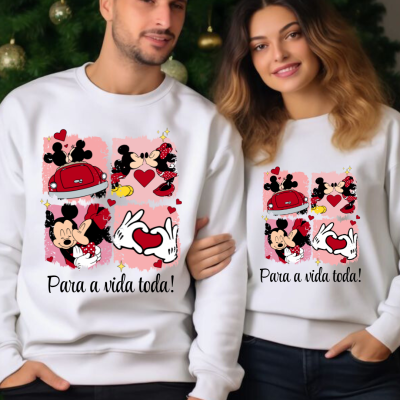 Casal com sweatshirts brancas de Mickey e Minnie com texto 'Para a vida toda!' em fundo de árvore de Natal