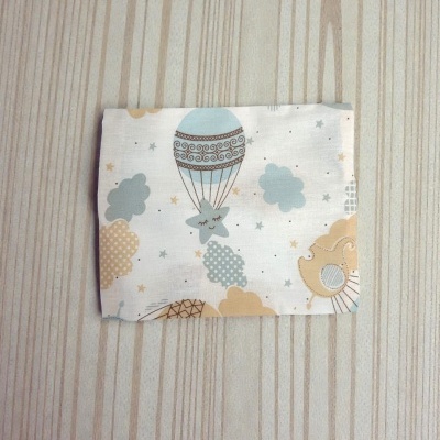 tecido dobrado com padrão infantil colorido sobre mesa de madeira clara