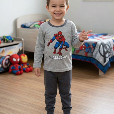 Menino vestido com pijama cinzento do Homem-Aranha em quarto infantil