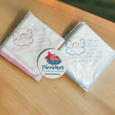 Dois panos de bebé bordados em algodão rosa e azul em mesa de madeira clara.