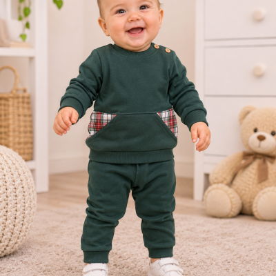 Bebé sorridente vestido com conjunto verde escuro com bolsos xadrez e sapatilhas brancas