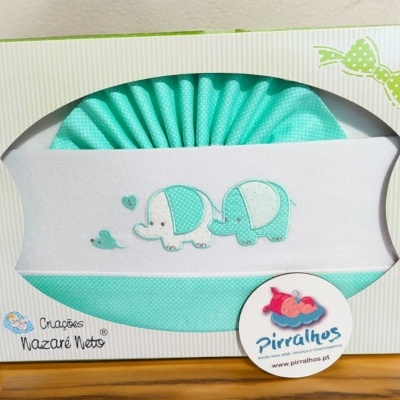 Fralda bordada para bebé branca e azul-turquesa com elefantes e corações numa caixa branca com detalhes verdes