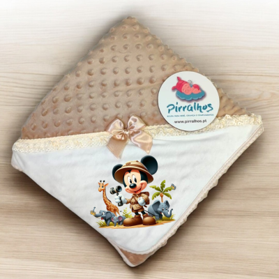 Manta castanha com textura, tecido branco com renda, laço bege, estampa do Mickey Mouse e etiqueta Pirralhos