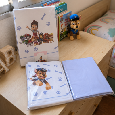 Conjunto de roupa de cama Patrulha Pata embalado sobre cómoda de madeira com livros e peluche ao lado