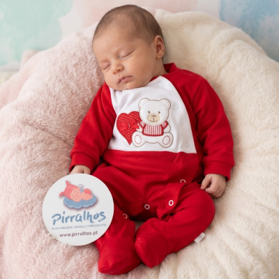 Bebé a dormir vestido com pijama vermelho e branco com estampa de urso e coração