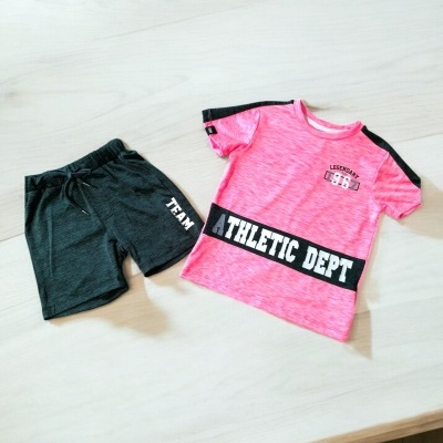 Conjunto de roupa desportiva rosa e preta com calções pretos sobre superfície de madeira clara