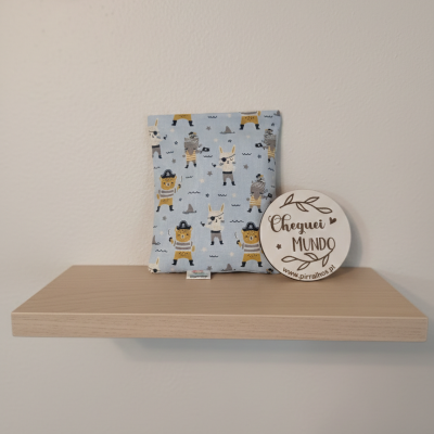 Almofada com padrão de piratas e placa com texto em prateleira de madeira