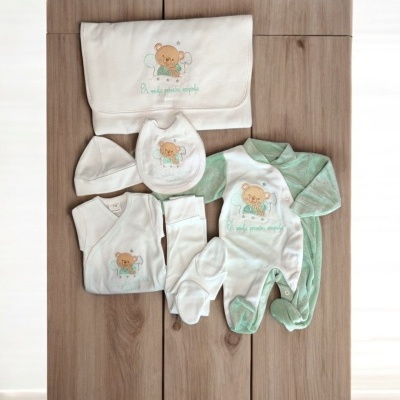 Conjunto de roupa de bebé branco e verde claro com ursinho e texto bordado, sobre mesa de madeira clara