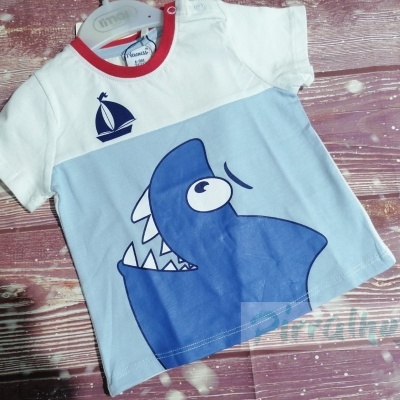 Camiseta infantil branca e azul com tubarão e vela, pendurada num cabide