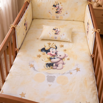 Roupa de berço amarela com estampa da Minnie Mouse a abraçar um ursinho e estrelas douradas em berço de madeira clara