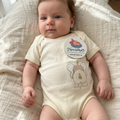 Bebé com body creme bordado, deitado em manta branca com estrelas