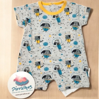 Macacão cinza claro com estampado de astronautas coloridos e gola amarela sobre fundo de madeira clara
