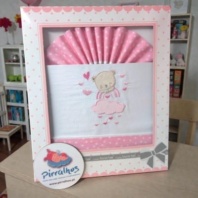 Fralda de bebé branca e rosa com bordado de urso em caixa rosa com bolinhas