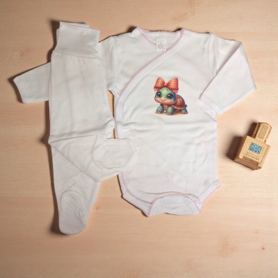 Conjunto de roupa de bebé branco com padrão de tartaruga e calças com pé em superfície de madeira clara