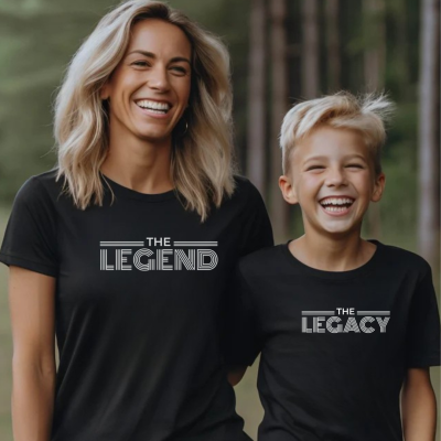 Duas pessoas com t-shirts pretas e texto branco 'THE LEGEND' e 'THE LEGACY' em ambiente exterior