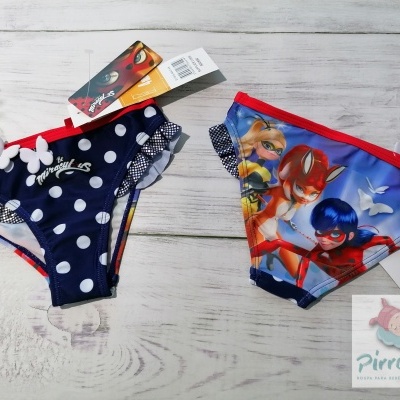 Cuecas de criança azul com bolinhas e colorida com personagens em fundo de madeira clara