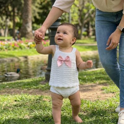 Roupa de bebé branca em malha com padrão ondulado e laço rosa