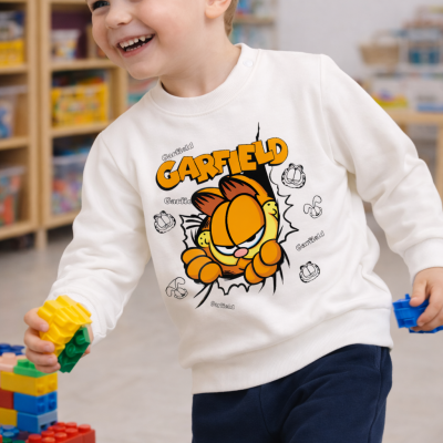 Camisola branca de criança com Garfield em ambiente interior com brinquedos.