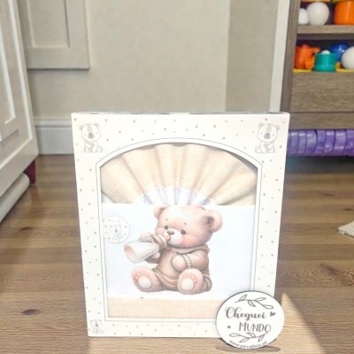 Caixa branca decorada com estrelas e ursinhos, contendo conjunto têxtil com desenho de ursinho a beber de mamadeira