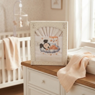 Conjunto de roupa de bebé em caixa com personagem a dormir e estrelas, sobre cómoda branca.
