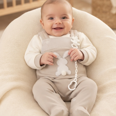 Bebé a sorrir sentado em sofá-beanbag creme com babygrow bege com padrão de coelho e fita de encaixe branca