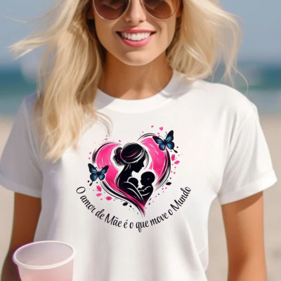 T-shirt branca com estampa de mãe e bebé em coração rosa e texto em português, usada por mulher na praia