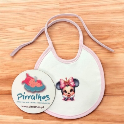 Babete branco com acabamento rosa e personagem Minnie Mouse ao centro, sobre madeira clara com etiqueta redonda Pirralhos ao lado