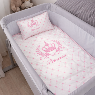 Berço cinza com roupa de cama branca e rosa com padrão Princesa