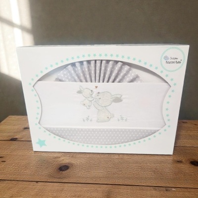 Conjunto de roupa de bebé com coelhos bordados e embalagem branca com estrelas azuis