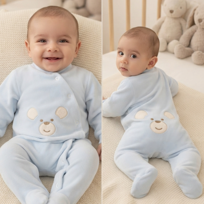 Bebé com macacão azul com rosto de urso sentado em fundo claro com ursos de peluche