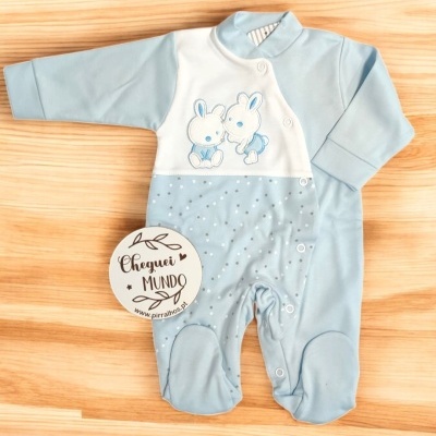 Pijama azul claro para bebé com coelhinhos e padrão de estrelas sobre fundo de madeira clara