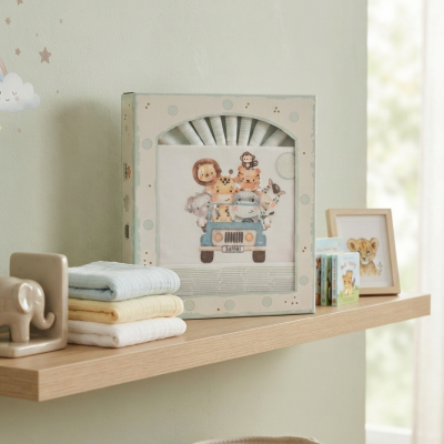 Prateleira com toalhas, roupa de bebê em caixa, livros infantis e quadro com imagem de leãozinho