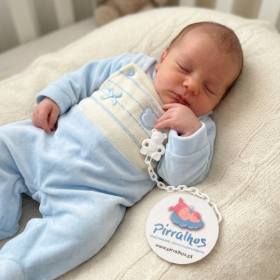Bebé dormindo com pijama azul claro junto a etiqueta redonda com logotipo Pirralhos