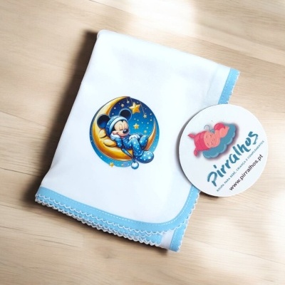 Toalha branca com borda azul e imagem de Mickey Mouse a dormir na lua e etiqueta Piralhos